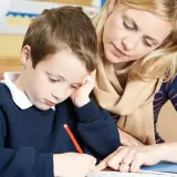 Nauczycielka pomaga chłopcu w nauce, wyjaśniając, co wlicza się do stypendium szkolnego.