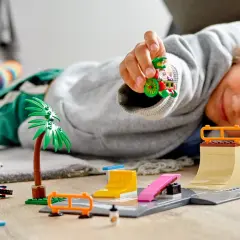 Chłopiec bawi się klockami, tworząc tor dla figurek. W tle widać samochód i palmy, a na pierwszym planie rampy i przeszkody do **zabawy konstrukcyjnej**.