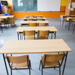 Puste ławki i krzesła w sali lekcyjnej czekają na uczniów. Obowiązek szkolny wkrótce wypełni te miejsca śmiechem i nauką.