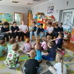 Młodzież czyta dzieciom w przedszkolu. Wspaniały przykład wolontariatu w przedszkolu, budujący relacje i rozwijający wyobraźnię najmłodszych.