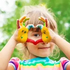 Radosne zabawy dla 4 latka! Dziecko maluje ręce farbami, tworząc serce i uśmiechnięte buźki.