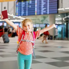 Uśmiechnięta dziewczynka z paszportem w ręku, gotowa do podróży. Jej obywatelstwo, jakie obywatelstwo ma dziecko urodzone za granicą, zależy od prawa kraju.
