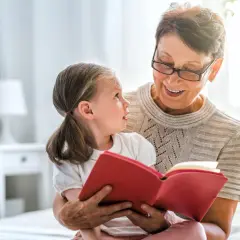 Uśmiechnięta opiekunka prawna czyta książkę małej dziewczynce.