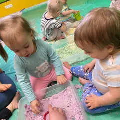 Dzieci bawią się kolorowym piaskiem księżycowym, tworząc swoje pierwsze dzieła.