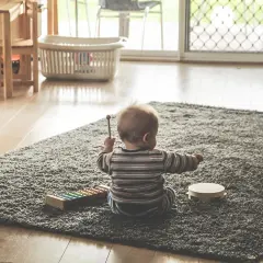 Maluch cieszy się muzycznymi zabawami, grając na cymbałkach i tamburynie.