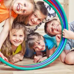 Uśmiechnięte dzieci bawią się kolorowymi obręczami, tworząc radosną scenę pełną zabawy ruchowej.