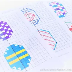 Kolorowe wzory na kratkowanym papierze, ćwiczące symetrię matematykę. Wzory przypominają jajka wielkanocne.
