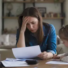 Zmartwiona kobieta z córką przy stole. Kto płaci alimenty jeśli ojciec nie płaci? Pytanie o finanse rodziny.
