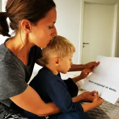 Mama pomaga 8-latkowi nauczyć się czytać, wspólnie czytają tekst "Rycerz przyjechał na koniu".