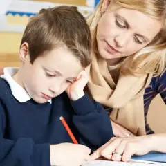 Nauczycielka pomaga chłopcu w nauce, wyjaśniając, co wlicza się do stypendium szkolnego.