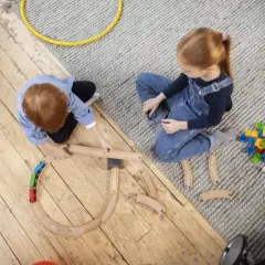 Dzieci budują tory kolejowe i bawią się klockami. Radosna zabawa w dom.