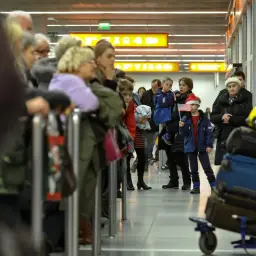 Dzieci z flagą USA i czapkami Mikołaja, w kolejce na lotnisku. Widać ulgę na powrót z zagranicy.