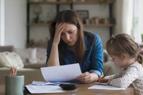 Zmartwiona kobieta z córką przy stole. Kto płaci alimenty jeśli ojciec nie płaci? Pytanie o finanse rodziny.