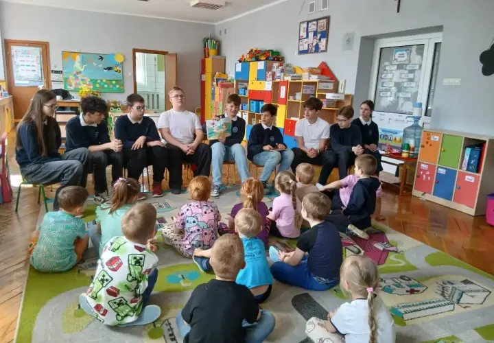 Młodzież czyta dzieciom w przedszkolu. Wspaniały przykład wolontariatu w przedszkolu, budujący relacje i rozwijający wyobraźnię najmłodszych.