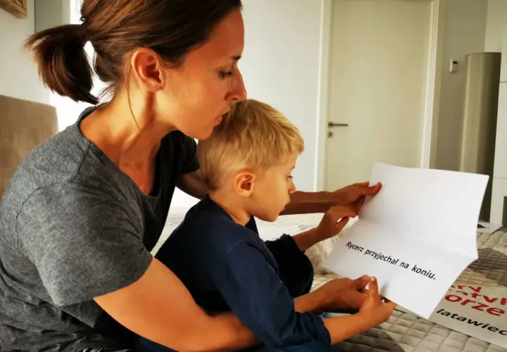 Mama pomaga 8-latkowi nauczyć się czytać, wspólnie czytają tekst "Rycerz przyjechał na koniu".