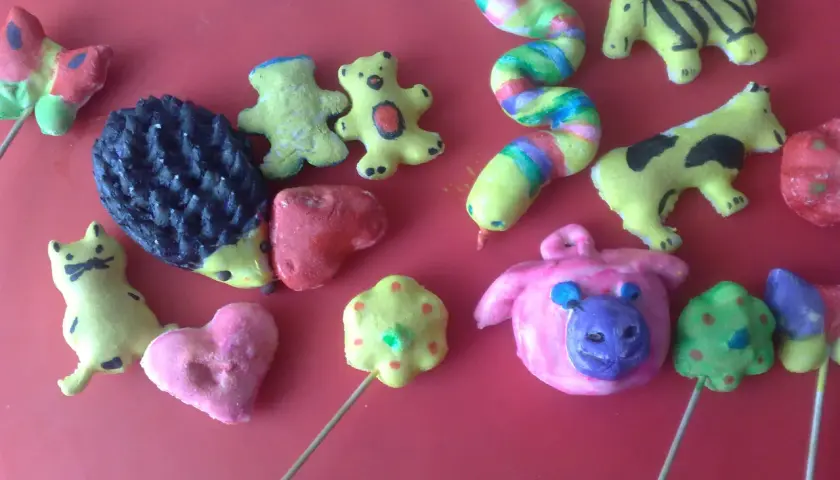 Kolorowe masy plastyczne z kuchennych składników uformowane w zwierzątka: jeża, kotka, misie, tygryska, krowę, świnkę i tęczowego węża.
