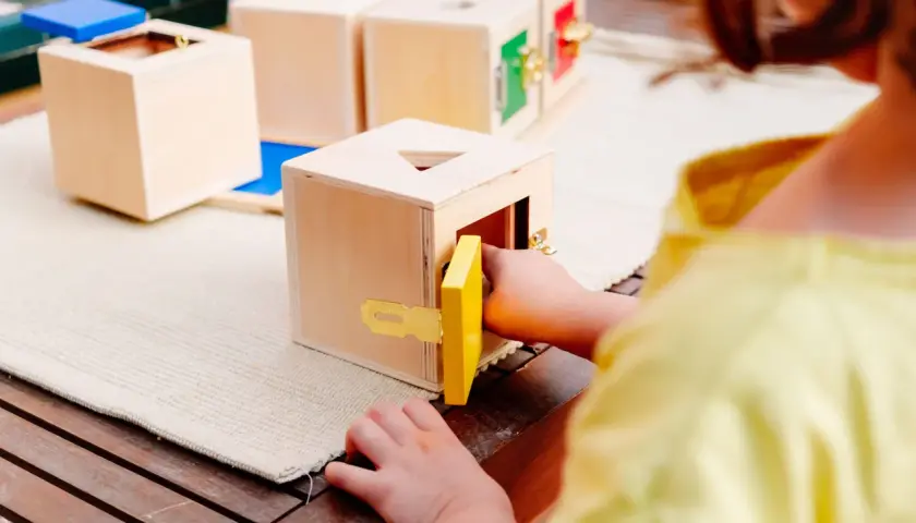 Dziecko bawi się drewnianymi sorterami kształtów, rozwijając zdolności manualne. Idealne zabawy sensoryczne dla 8 miesięcznego dziecka.