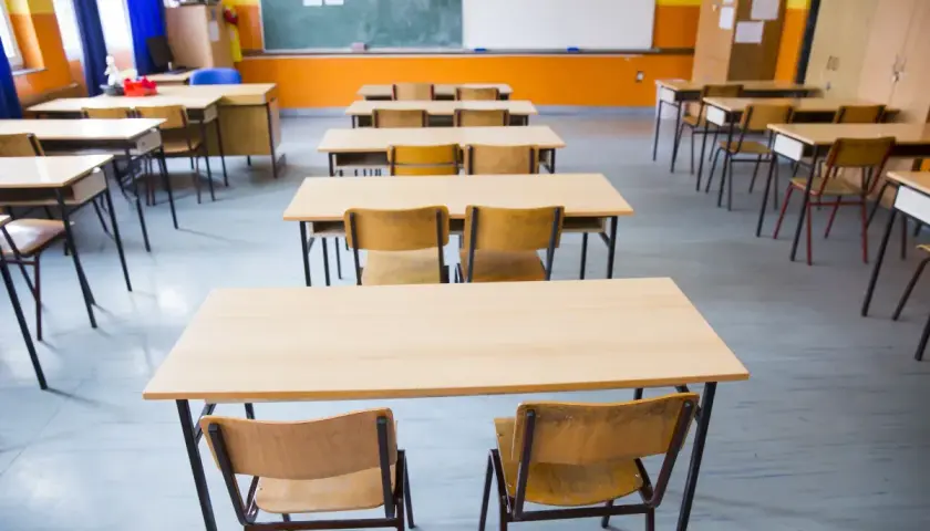 Puste ławki i krzesła w sali lekcyjnej czekają na uczniów. Obowiązek szkolny wkrótce wypełni te miejsca śmiechem i nauką.
