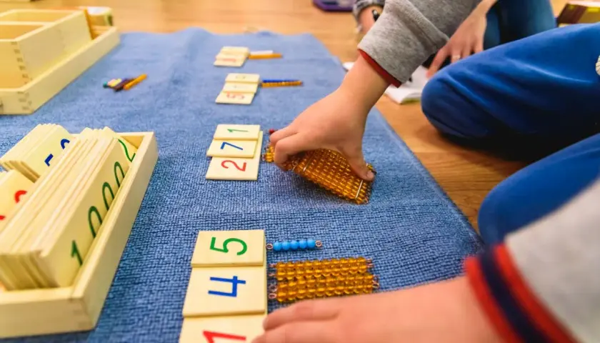 Dzieci bawią się matematycznie, układając klocki z cyframi i koraliki.