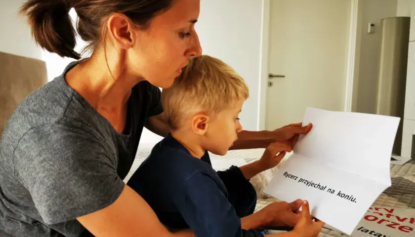 Mama pomaga 8-latkowi nauczyć się czytać, wspólnie czytają tekst "Rycerz przyjechał na koniu".