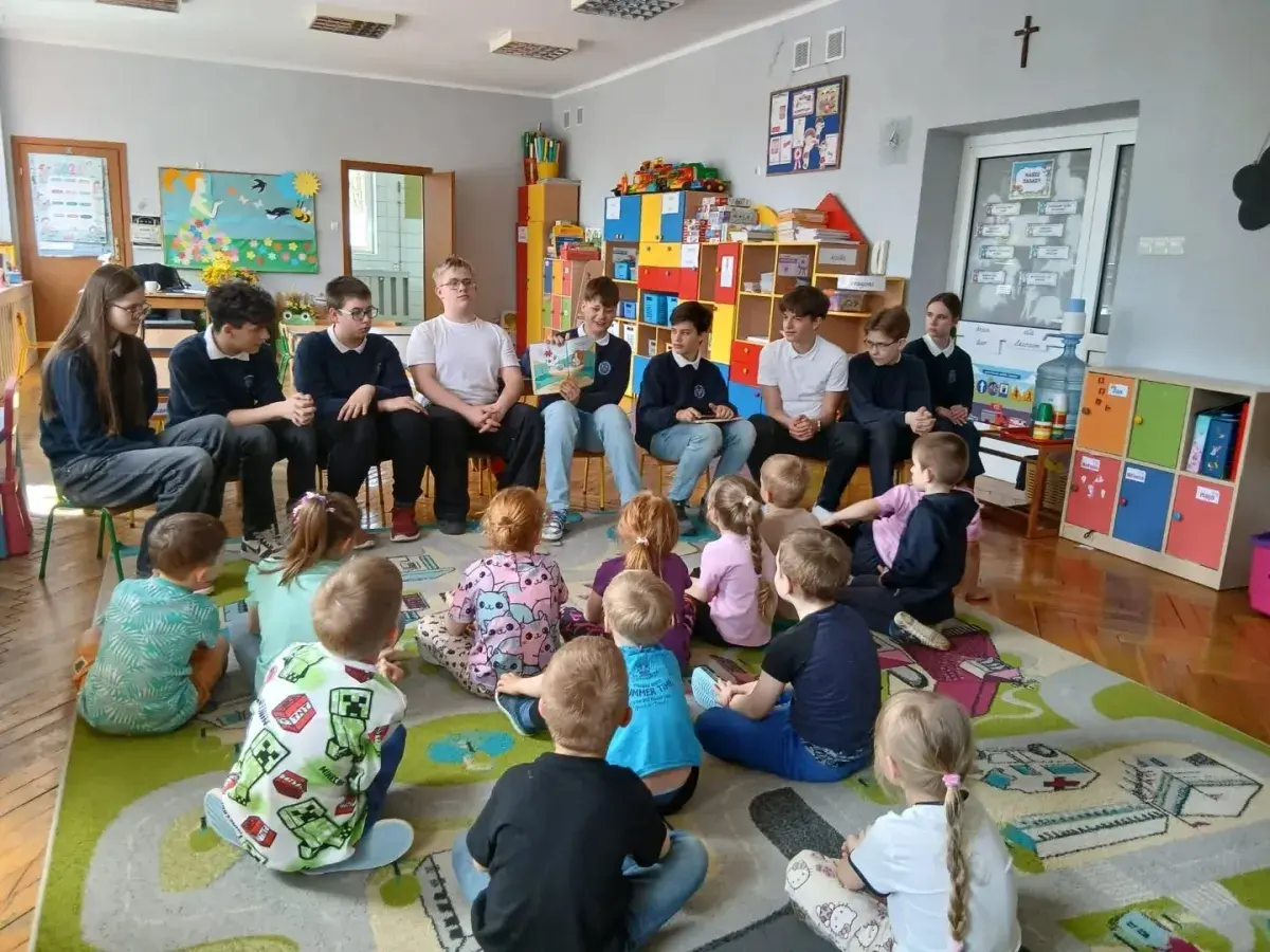 Młodzież czyta dzieciom w przedszkolu. Wspaniały przykład wolontariatu w przedszkolu, budujący relacje i rozwijający wyobraźnię najmłodszych.