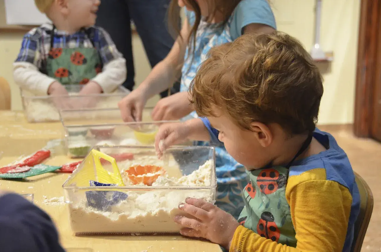 Dzieci bawią się masą sensoryczną, tworząc piaskowe zamki. Świetne zabawy sensoryczne dla 7 latka!