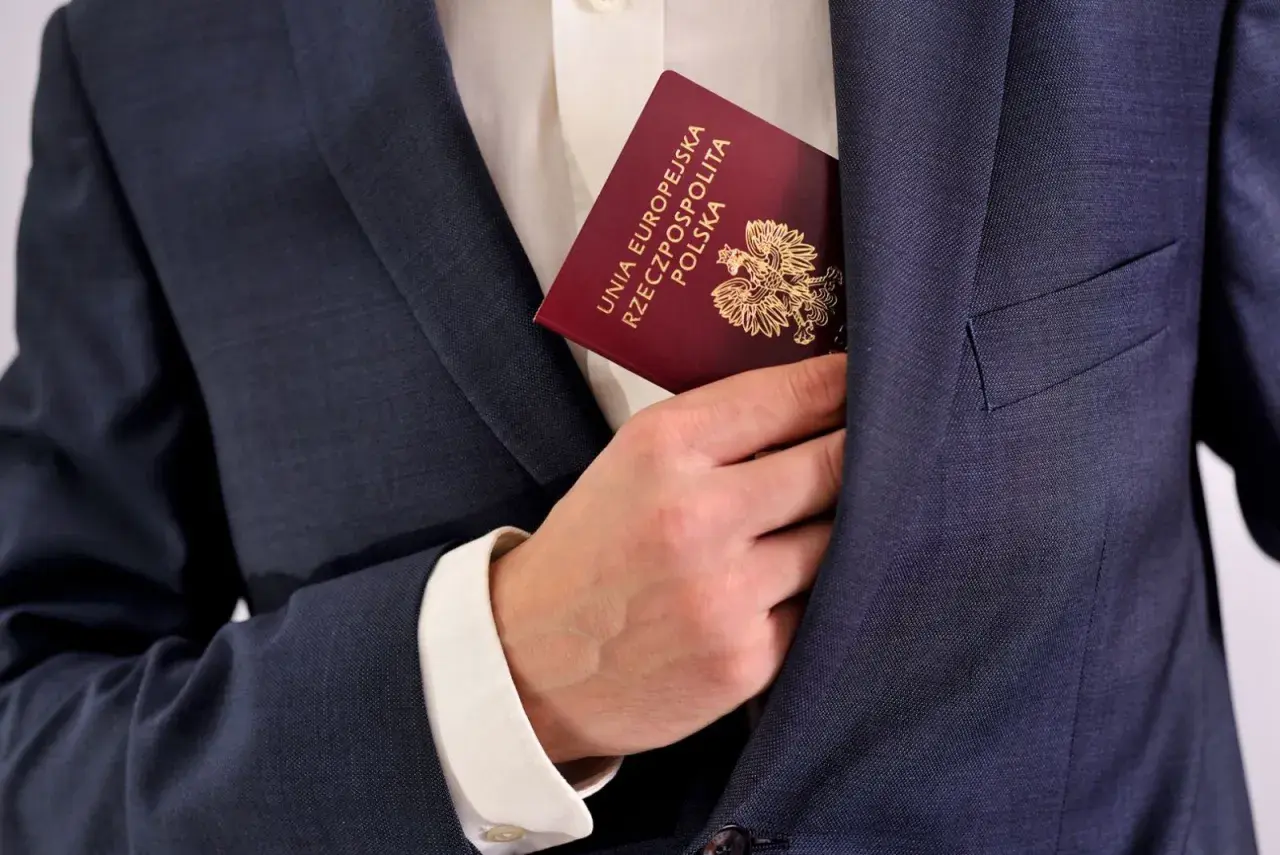 Dłoń wsuwa polski paszport do kieszeni marynarki. Dokument potwierdza, że osoba posiada obywatelstwo.