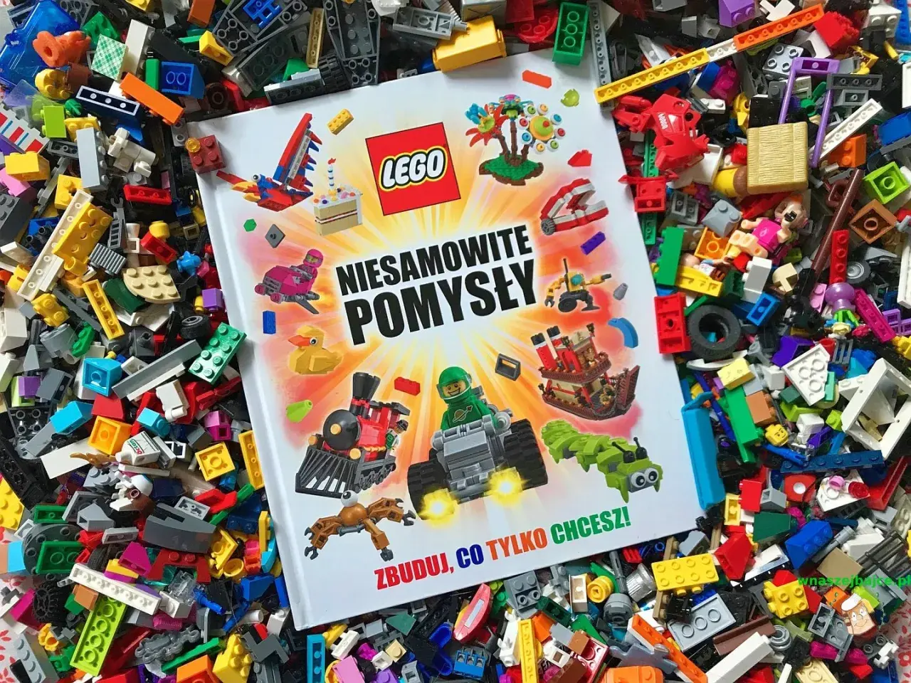 Książka LEGO "Niesamowite pomysły" leży na morzu klocków, inspirując do budowania wszystkiego, co tylko chcesz.