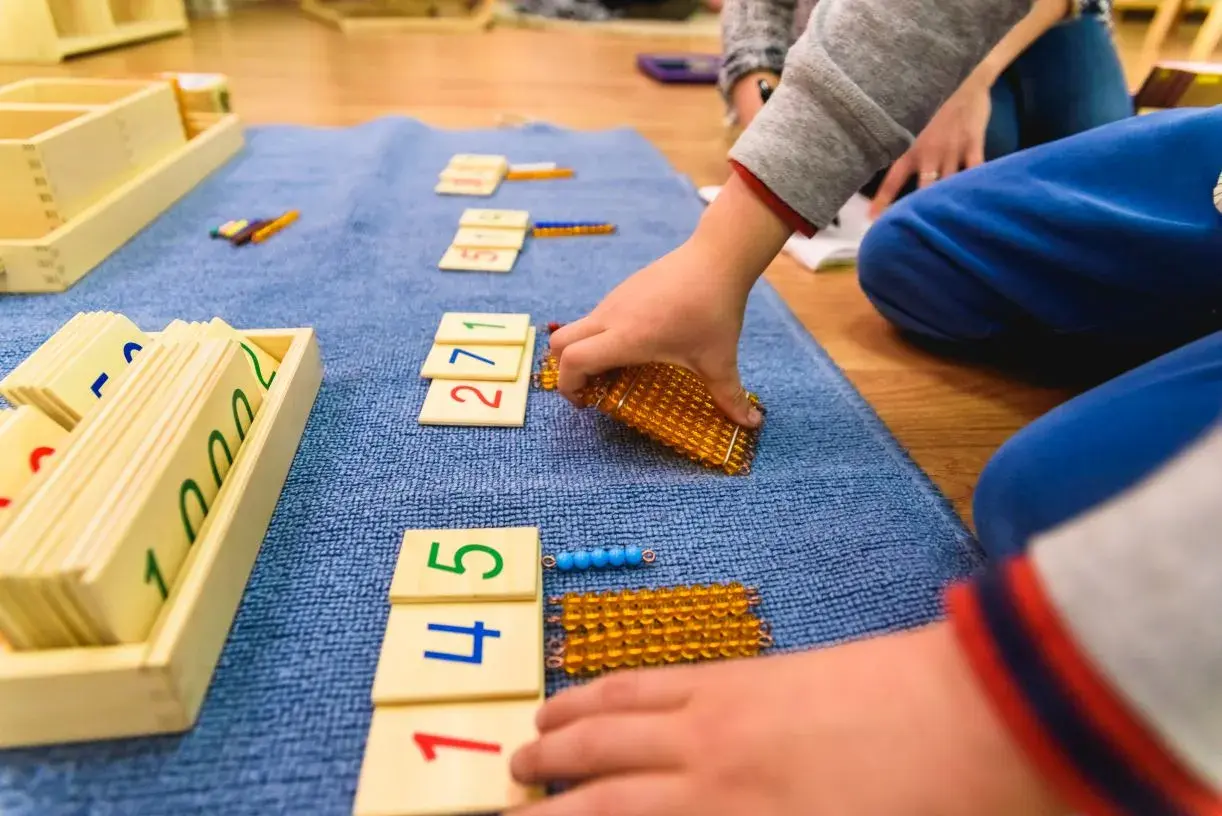 Dzieci bawią się matematycznie, układając klocki z cyframi i koraliki.