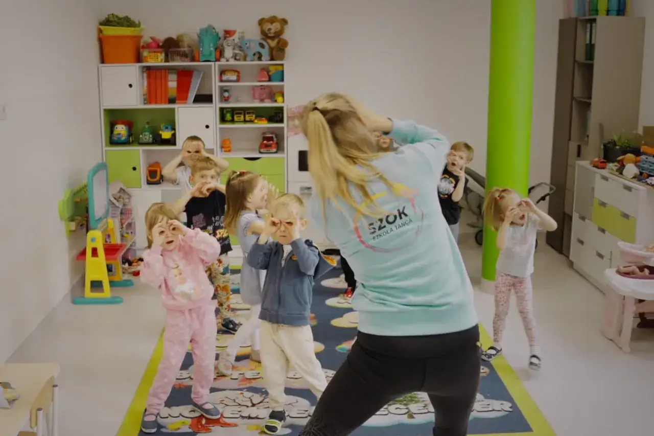 Dzieci na zajęciach tańca wykonują ciekawe zabawy taneczne, naśladując ruchy nauczycielki.